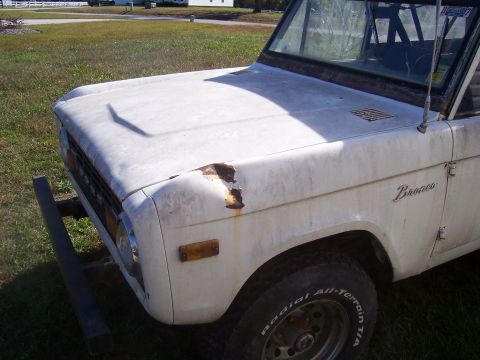 1974 Ford Bronco - A white 1974 Ford Bronco is shown from the front passenger side, with visible rust and wear.