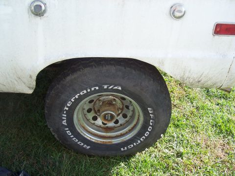1974 Ford Bronco - Close-up of a white vehicle's rear wheel and fender, showing a BFGoodrich tire.