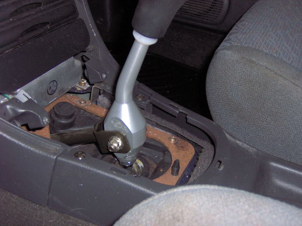 Silver short-throw shifter installed with console trim removed in a car interior
