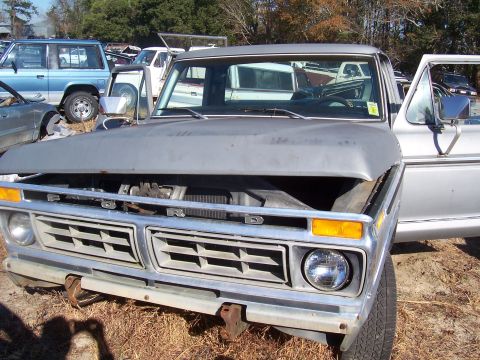 1978 Ford Bronco - This silver Ford pickup truck, likely from the mid-1970s, is seen in a junkyard with its hood open.