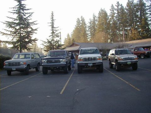 1994 Ford Explorer - Several SUVs are parked in a lot with trees and a building in the background.