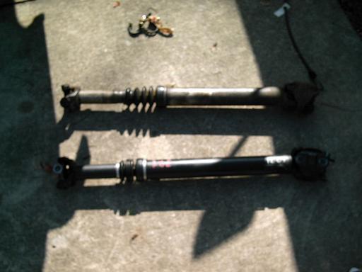 Two driveshafts, one with red markings, on concrete