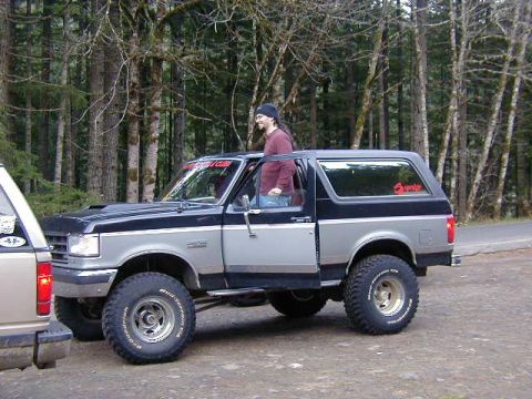 1994 Ford Explorer - A two-tone Ford Bronco is parked outdoors with a man visible in the driver's seat.
