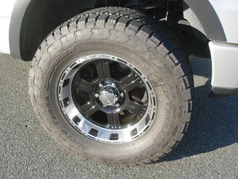 1995 Ford Bronco - This image shows a close-up view of a vehicle's wheel and tire, Nitto Terra Grappler tires and a black and chrome aftermarket wheel.