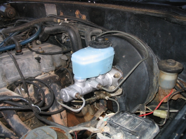 Close-up of a brake master cylinder and reservoir in an engine bay