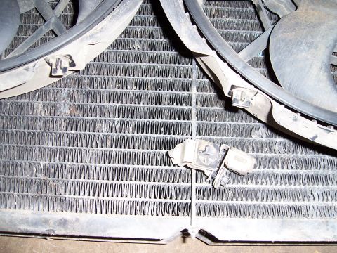1983 Ford Bronco - Close-up view of a vehicle's radiator and electric fans, with a sensor mounted on the radiator fins.