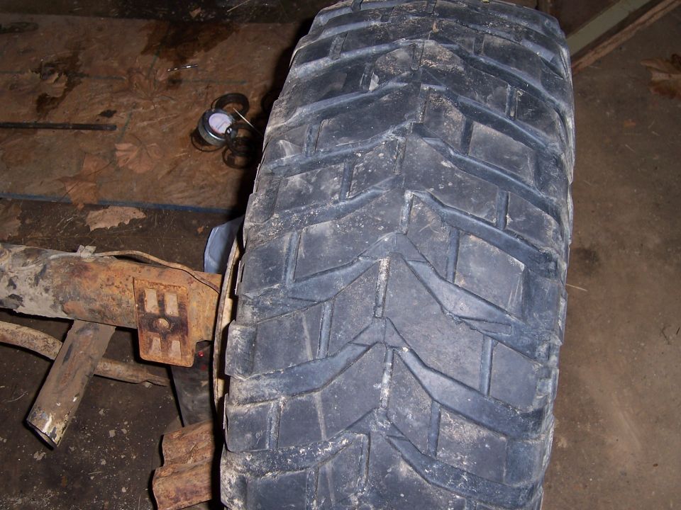 Close-up of a large off-road tire and rusty suspension component