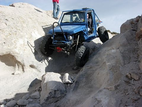 1987 Ford Bronco - A heavily modified blue buggy navigates a challenging rock crawling course.