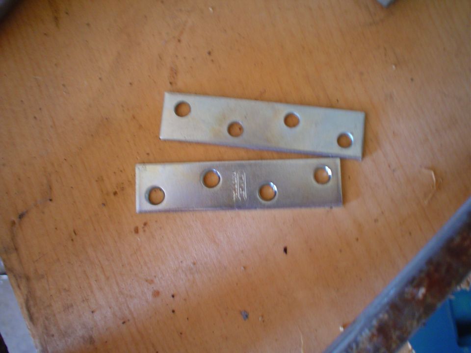 Two metal plates with holes on a wooden surface