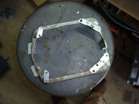 1984 Ford Bronco - A metal bracket assembly is mounted on a circular object, possibly for repair or modification.