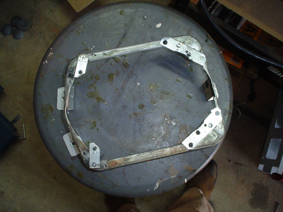 Metal bracket assembly attached to a round, dark surface with visible screws and metal plates