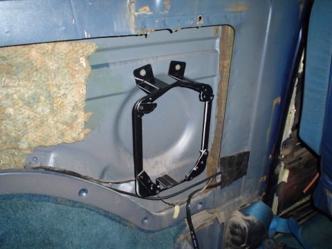 1984 Ford Bronco - The interior of a blue vehicle shows exposed insulation and a black metal bracket attached to the side panel.