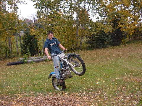 1985 Ford F-150 - A man performs a wheelie on a dirt bike in a grassy outdoor setting during autumn.