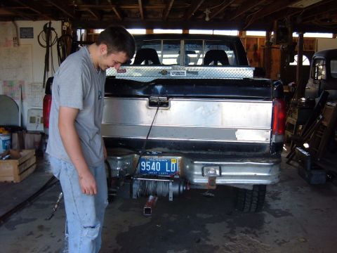 1985 Ford F-150 - A man inspects the rear of a pickup truck, which appears to be a Ford model from the late 1980s.