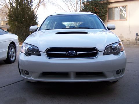 2005 Subaru Legacy - A white Subaru Legacy is parked outside a building, with another vehicle to its side.