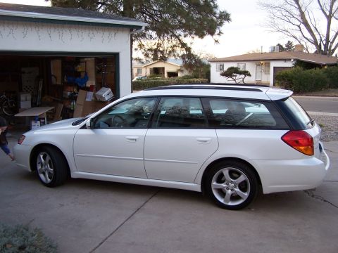 2005 Subaru Legacy - A white 2005 Subaru Outback wagon is parked in front of a garage and house.