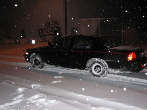 2000 Ford Crown Victoria - A black 2000 Ford Crown Victoria navigates through a snowy environment at night.