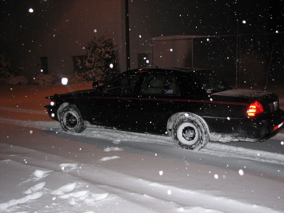 Black 2000 Ford Crown Victoria driving in snow