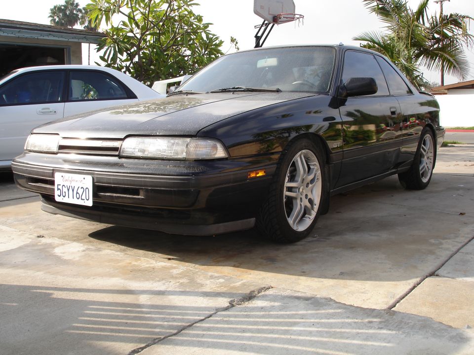 1989 Mazda MX-6 parked in a driveway with another car behind it