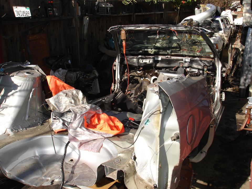Deconstructed car interior with exposed wires and orange tarp covering parts