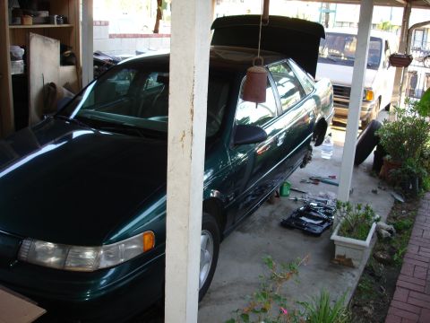1995 Ford Taurus - 1995 Ford Taurus undergoing maintenance, with front wheels off and tools laid out.