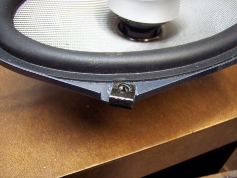 1995 Ford Probe - A car speaker is shown with its mounting bracket and screw, resting on a wooden surface.