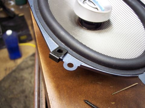 1995 Ford Probe - A car speaker is shown close-up, resting on a wooden surface with a screw nearby.