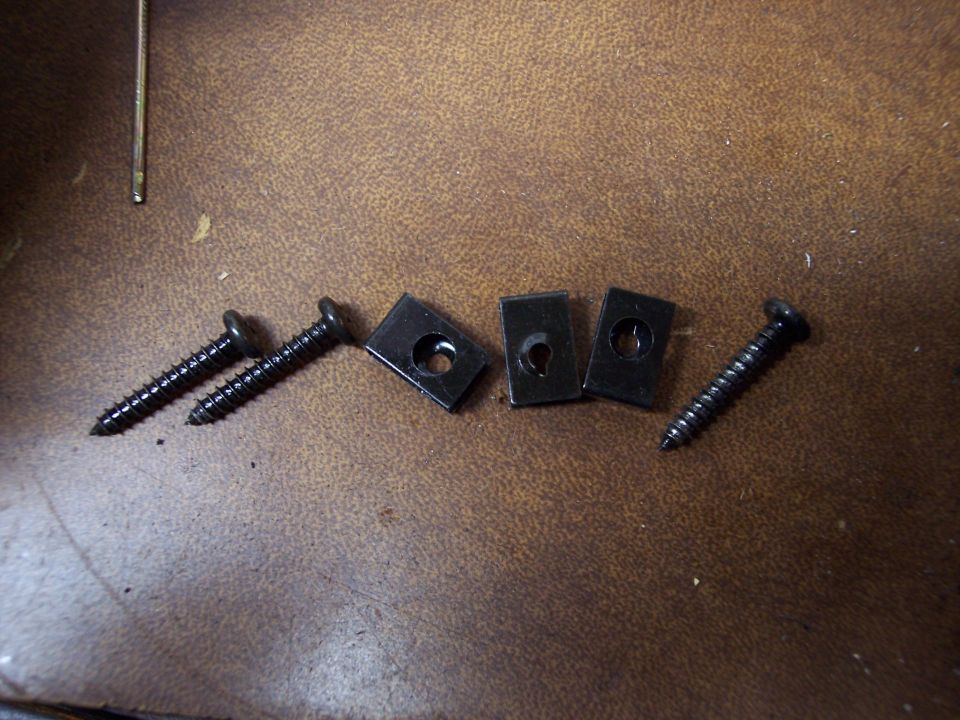 Black screws and U-nuts on brown textured surface
