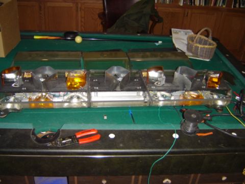 1992 Ford Bronco - Disassembled light bar components and tools are laid out on a pool table.