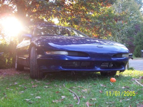 1994 Ford Probe - A blue 1994 Ford Probe is seen from the front, parked on a grassy lawn with trees in the background.