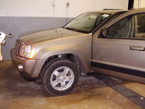 1997 Ford Taurus - A gold Jeep Grand Cherokee is parked inside a garage with its driver's door open, showing the interior.
