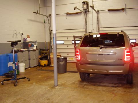 1997 Ford Taurus - Rear view of a gold Jeep Compass parked inside a garage with its doors open. The vehicle has visible text that reads SUPERMOTORS.