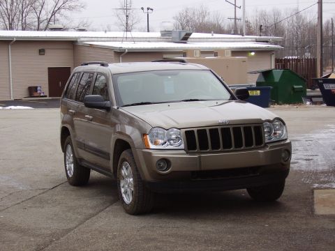 1997 Ford Taurus - A Jeep Grand Cherokee is parked in a lot with snow on the ground and dumpsters nearby.