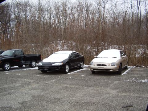 1997 Ford Taurus - A gold 1997 Ford Taurus is parked in a lot covered with a light dusting of snow.