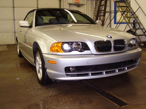 1997 Ford Taurus - A silver BMW convertible is parked inside a garage with a ladder and garage door in the background.