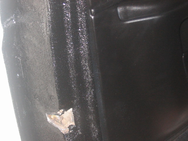 close-up of black interior panel with some texture and a small damaged metal piece