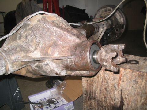 1994 Jeep Cherokee - Close-up of a heavily corroded differential housing with a U-joint yoke, supported by a wooden block.