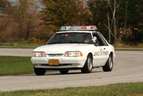 1993 Ford Mustang - A white 1993 Ford Mustang police car is seen from the front-three-quarter view, displaying "STATE POLICE" on its side.