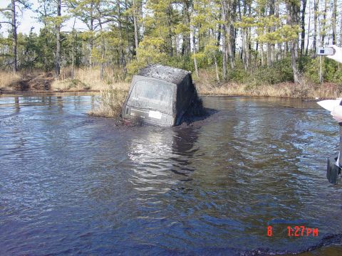 1995 Dodge 1500 - A 1995 Dodge 1500 is stuck in a muddy body of water, with only its rear visible.