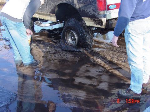 1995 Dodge 1500 - A truck is stuck in the mud with a flat tire, as two individuals observe the situation.