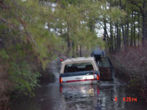 1995 Dodge 1500 - A 1995 Dodge 1500 is partially submerged in water, with a person climbing out of the passenger door.