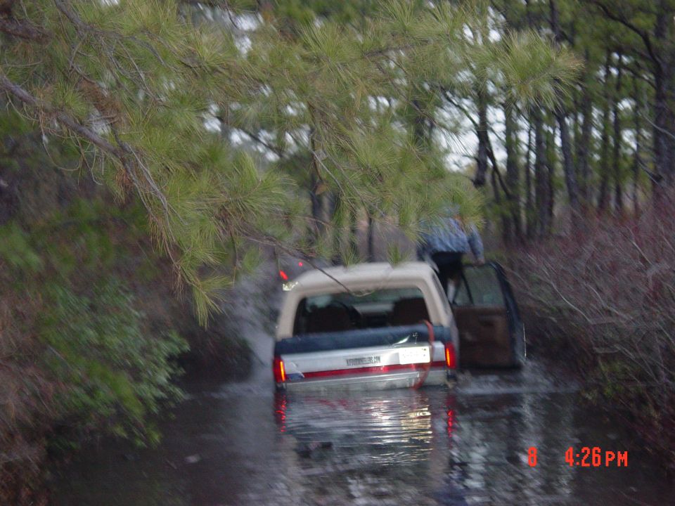 Rear view of a 1995 Dodge 1500 stuck in water, with a person exiting the passenger side