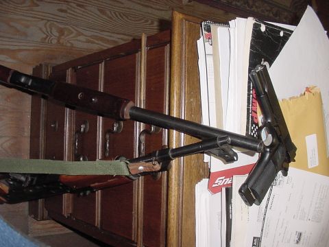 1969 Ford Bronco - A handgun and rifle are placed on top of a wooden cabinet next to a pile of documents.