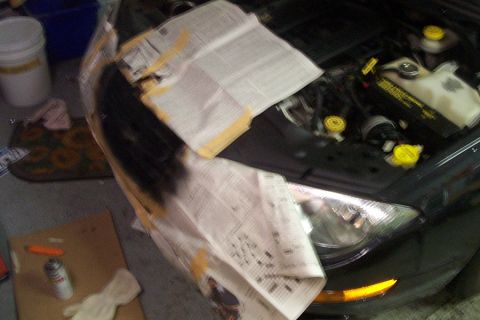 1999 Chrysler 300M - A car's engine bay is partially covered with newspapers, with tools and supplies for a repair or painting project visible.