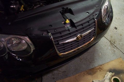 1999 Chrysler 300M - Front view of a black Chrysler grille with chrome accents and headlight.
