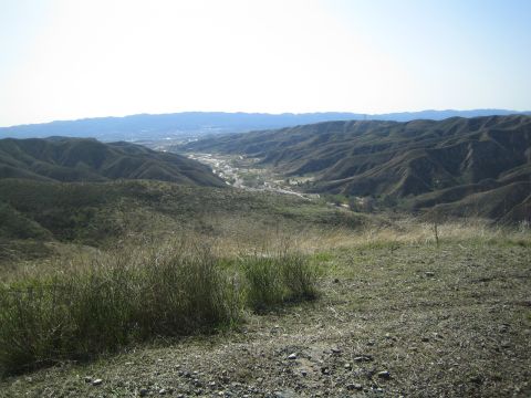 1990 Ford Bronco - panoramic view from a hilltop down a valley toward a distant town nestled among rolling brown hills.