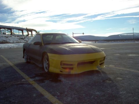 1994 Ford Probe - A two-tone Ford Probe is parked in an empty lot under a cloudy sky.