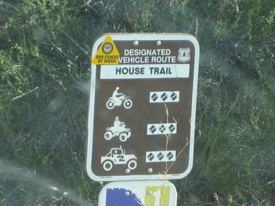 Close-up of a brown HOUSE TRAIL designated vehicle route sign with difficulty icons