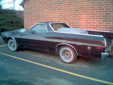 1972 Ford Ranchero - A 1972 Ford Ranchero is parked on asphalt with a yellow line in front of a brick building.