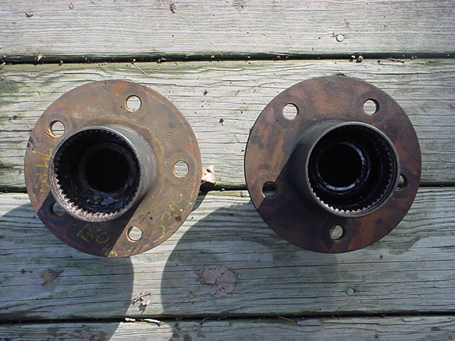 Two rusty wheel hubs with splined centers on a wooden surface
